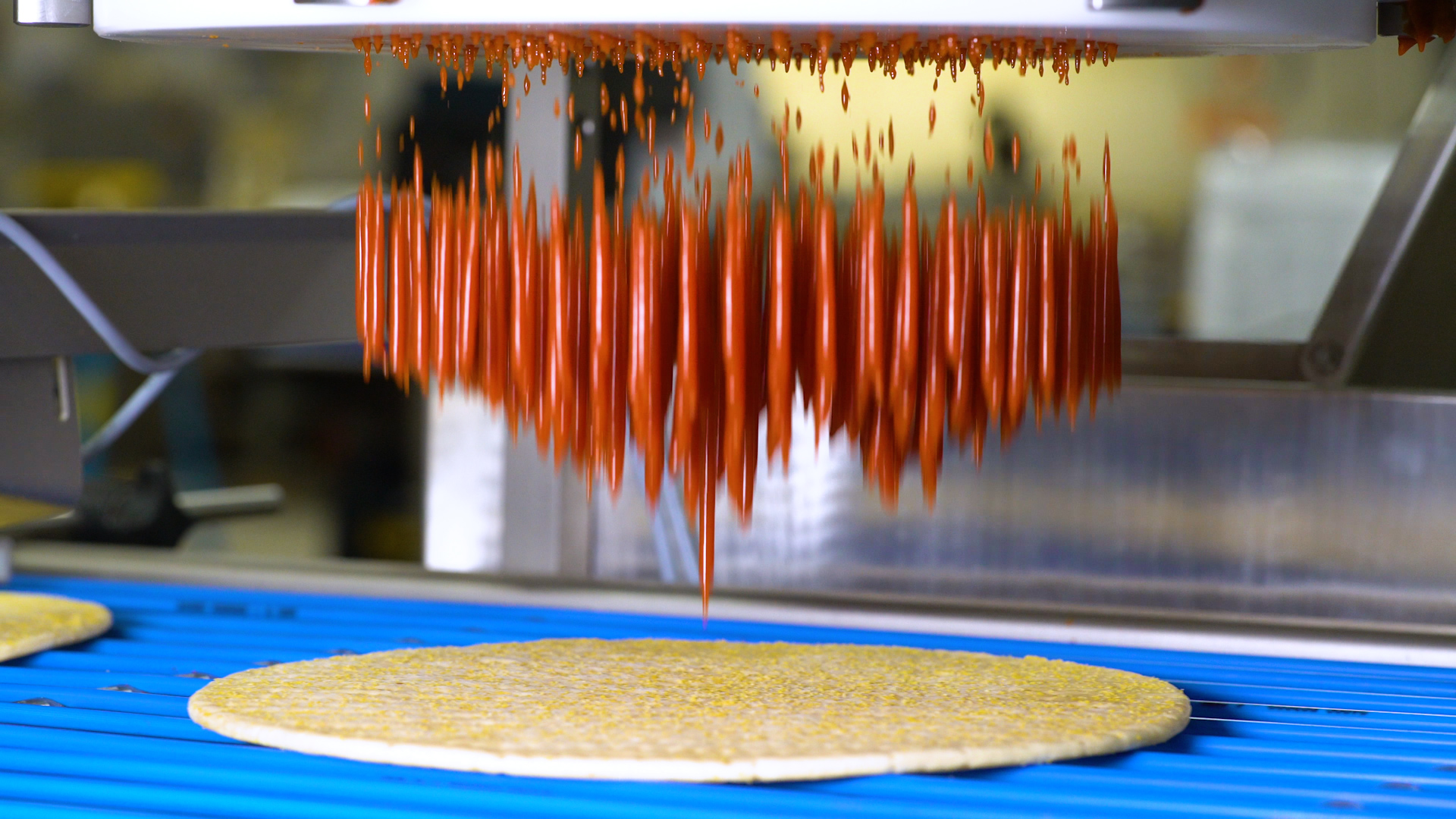 Sauce being applied to a pizza crust from a sauce applicator machine. 